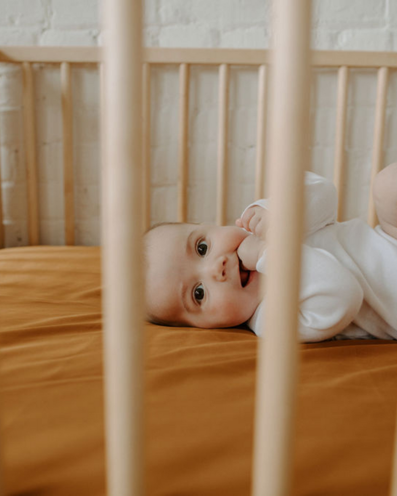 Bébé dans un lit avec literie couleur safran.
