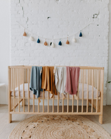 Doudous couleurs bleu profond, rose antique, caramel et greige dans une chambre de bébé.