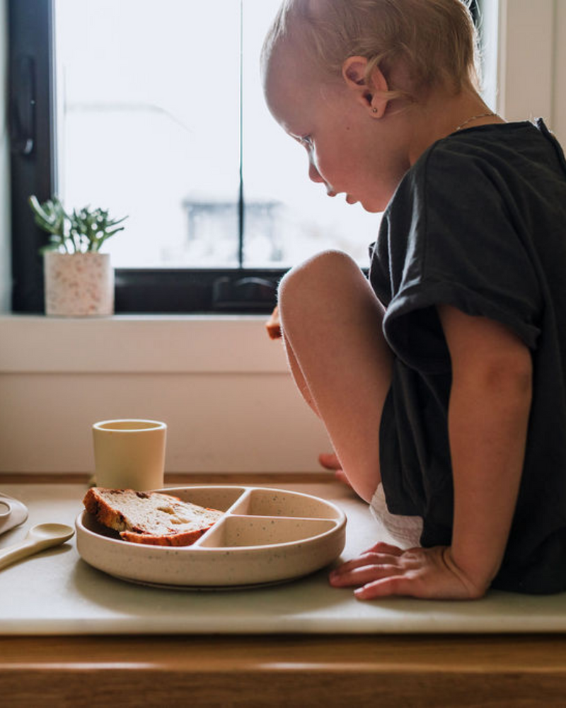 Enfant qui mange avec vaisselle en silicone couleur maïs.