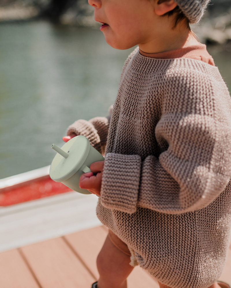 Enfant sur le quai avec verre à paille en silicone dans les mains.